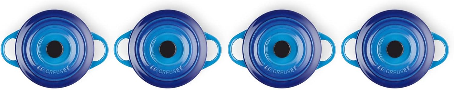 Le Creuset’s miniature azure casserole dish, complete with a matching lid—sitting pretty on a rustic wooden table. Its vibrant colour pops against the natural grain, inviting you to imagine the delicious meals it could hold. Perfect for bite-sized servings or side dishes.