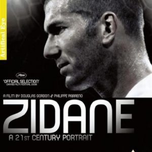Close-up shot of Zinedine Zidane—his legendary face, neutral and contemplative against a soft backdrop. You can almost feel the weight of his football history in this moment.