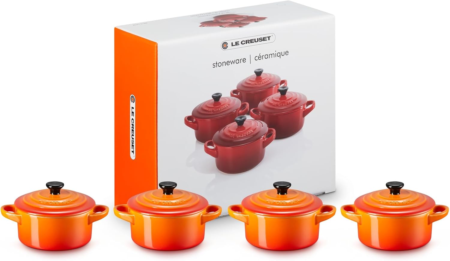 Four charming blue Le Creuset Miniature Round Casseroles—arranged just so, on a rustic wooden table. Perfectly sized for those personal servings. Their elegant curves catch the light, making them look almost too good to eat from.