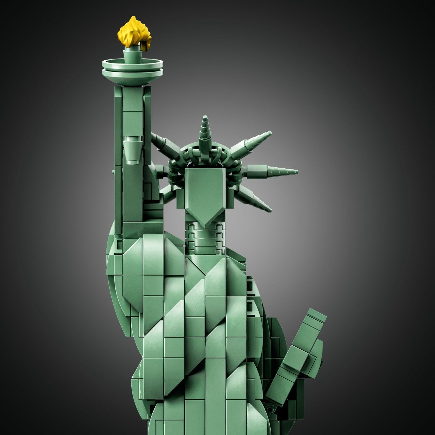 An intricate LEGO® Architecture model of a statue—complete with a flowing robe and pedestal, plus a shiny golden torch. It's all set against a stark white backdrop, really makes those details pop.