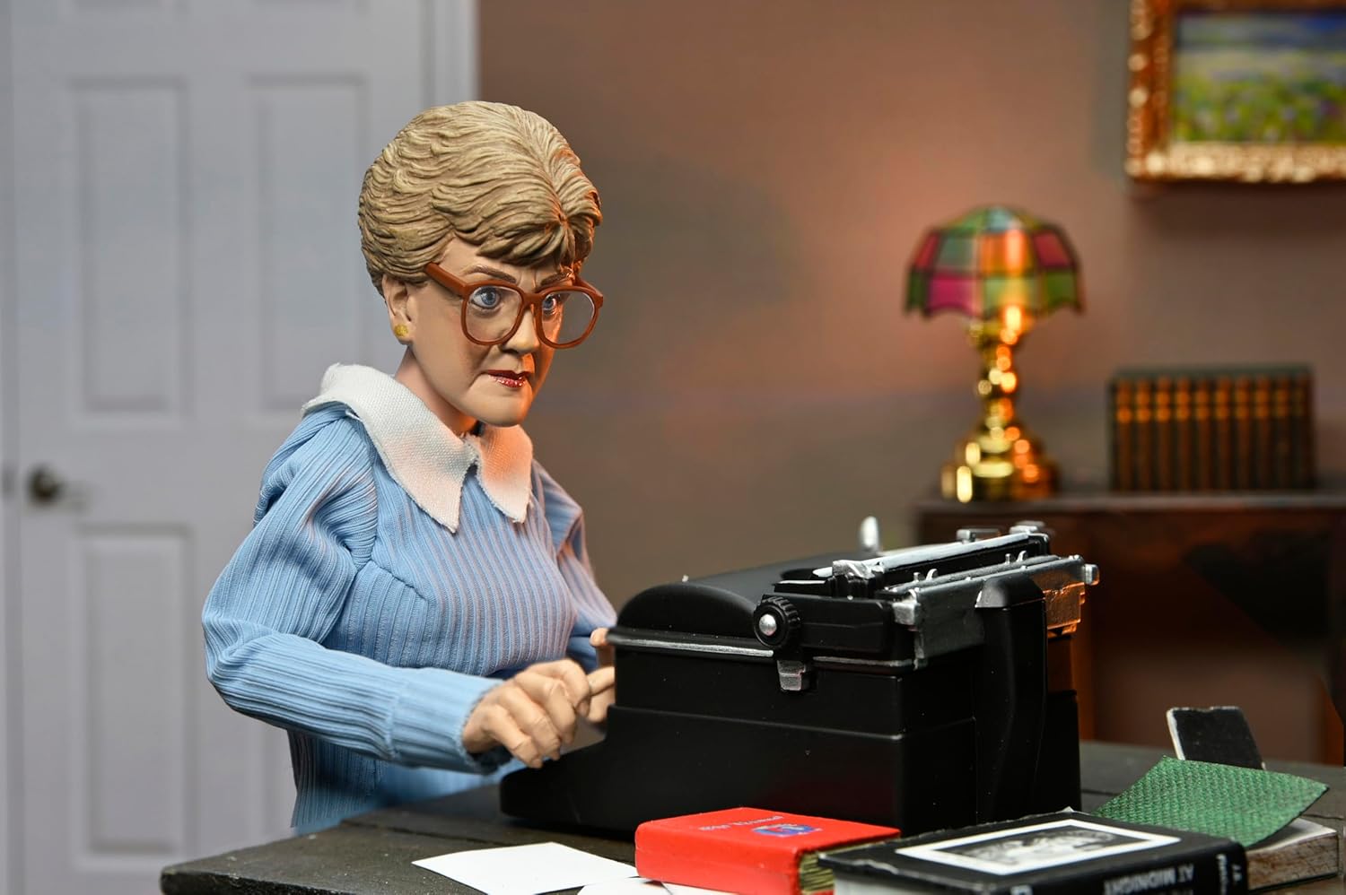 Jessica Fletcher doll rocking a chic floral dress, complete with her iconic hairstyle—she's clutching a notepad, ready to solve the next mystery. The backdrop? Super plain, letting her style steal the show.