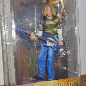 Kurt Cobain action figure—rocking that iconic grey sweater and jeans combo, clutching a guitar like it’s an extension of his soul. Pure nostalgia, against a crisp white backdrop; it just hits different.