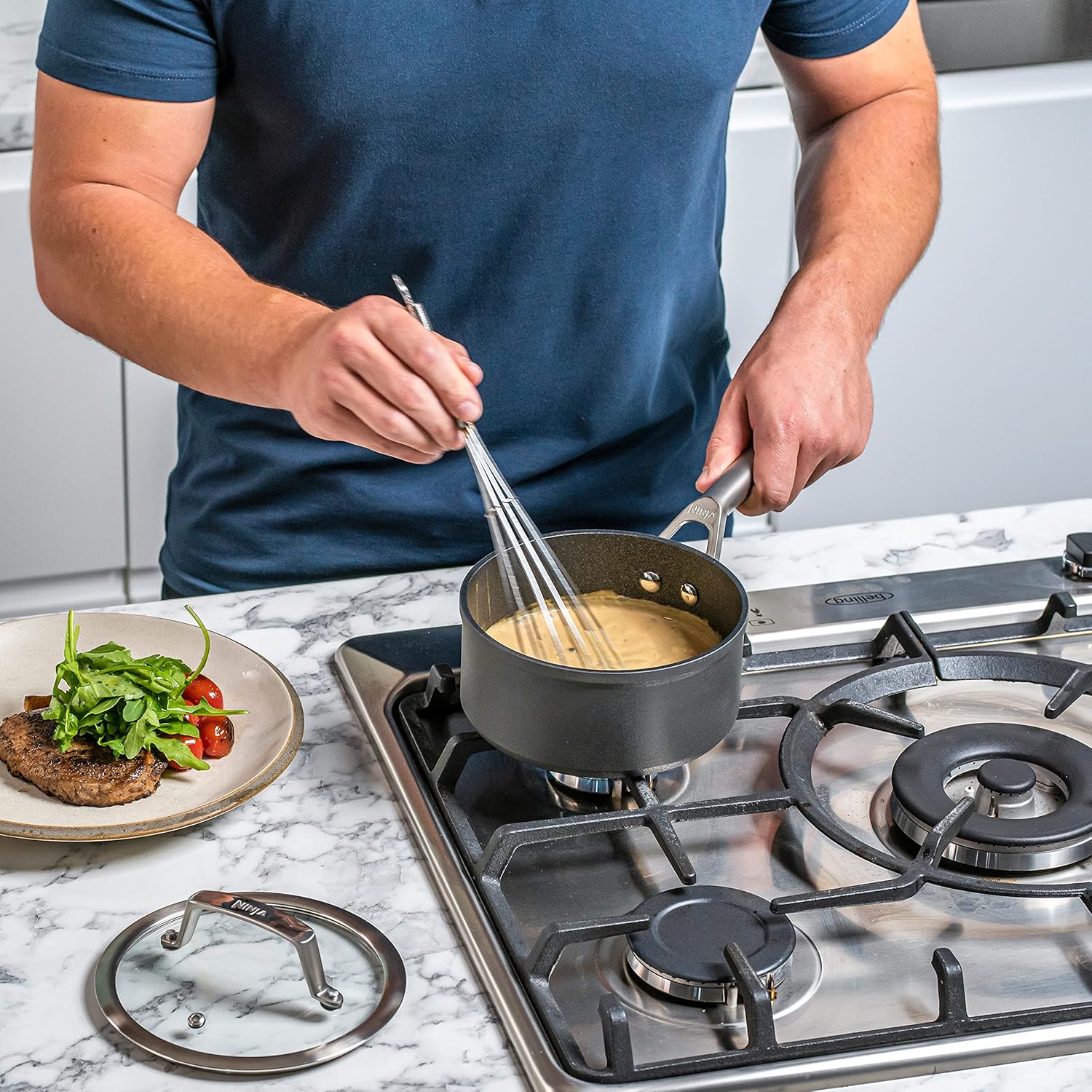 28cm Ninja wok, sleek grey non-stick surface—perfect for stir-fries and more. Glass lid, so you can peek without losing heat. Just sitting there on a rustic wooden counter, like it knows it’s the star of the kitchen show.